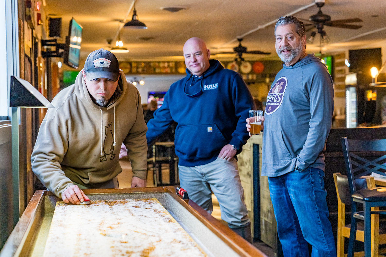 3 Guys Playing Shuffle Board at 4 Dogs Brewing Co. and Pub